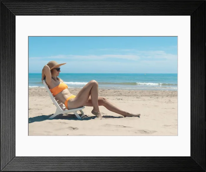 Framed Print : Portrait of a happy woman in an orange swimsuit sunbathing on a plastic sun lounger on a tropical Framed Print : Portrait of a happy woman in an orange swimsuit sunbathing on a plastic sun lounger on a tropical