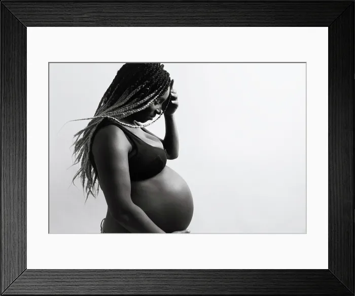 Framed Print : Cheerful young pregnant black female with braids touching belly Framed Print : Cheerful young pregnant black female with braids touching belly