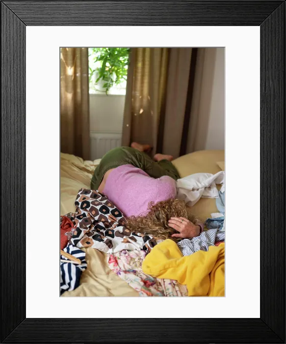 Framed Print : menopause Woman lying face down on a messy bed with clothes scattered around Framed Print : menopause Woman lying face down on a messy bed with clothes scattered around