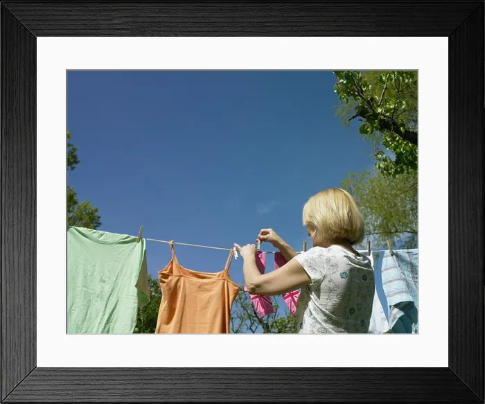 Framed Print : Woman hanging clothes on clothesline Framed Print : Woman hanging clothes on clothesline