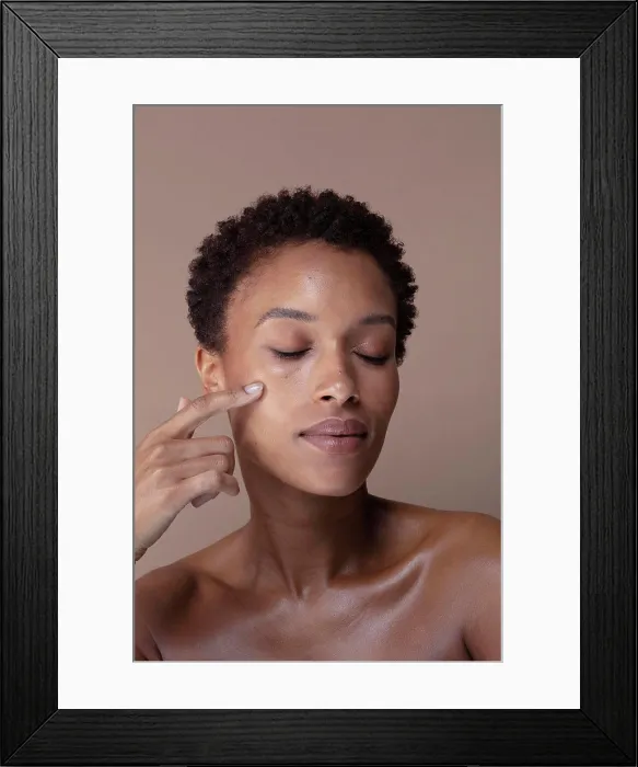 Framed Print : Studio shot of woman with eyes closed touching face Framed Print : Studio shot of woman with eyes closed touching face