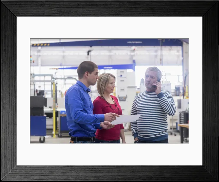 Framed Print : Business people showing document to mature businessman talking on phone Framed Print : Business people showing document to mature businessman talking on phone