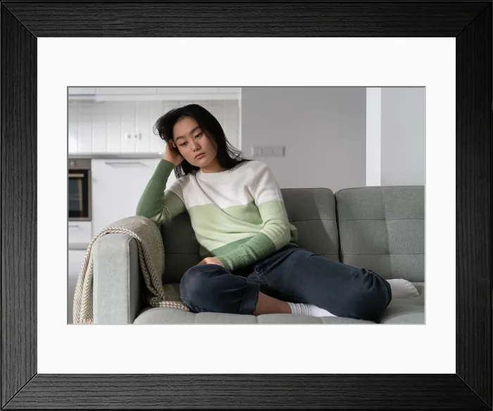 Framed Print : Sad, angry chinese sits on the sofa and suffers from depression after she has separated from her boyfriend Framed Print : Sad, angry chinese sits on the sofa and suffers from depression after she has separated from her boyfriend