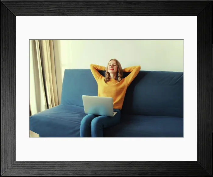 Framed Print : Glückliche junge Frau entspannt sich bei der Arbeit am Laptop Framed Print : Glückliche junge Frau entspannt sich bei der Arbeit am Laptop