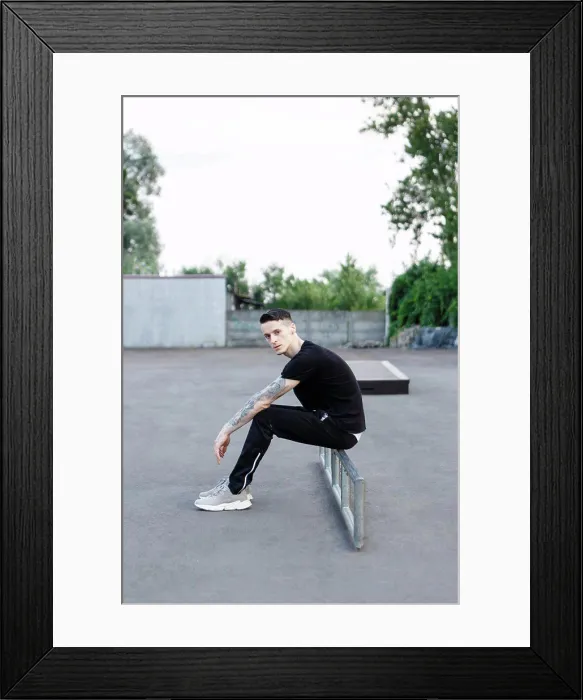 Framed Print : young brunette man sitting alone on an asphalt skate playground Framed Print : young brunette man sitting alone on an asphalt skate playground