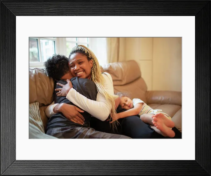 Framed Print : Happy mother hugging son on living room sofa