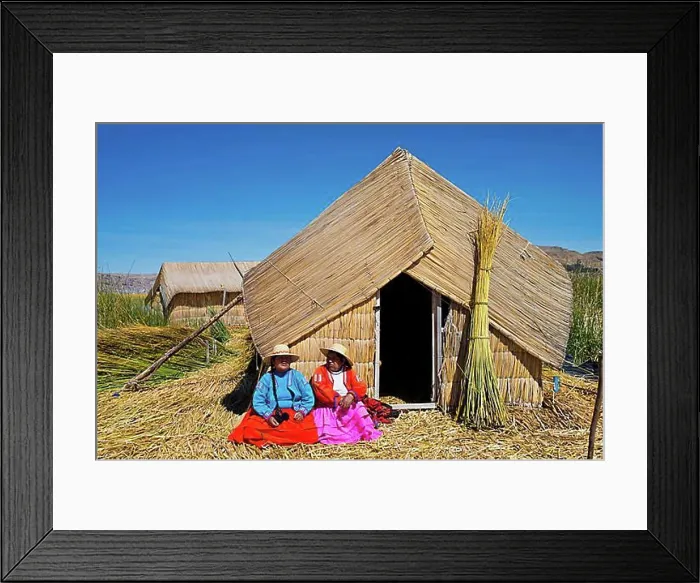 Framed Print : Two women of the Uro Indians wearing traditional dress sitting in front of a reed hut