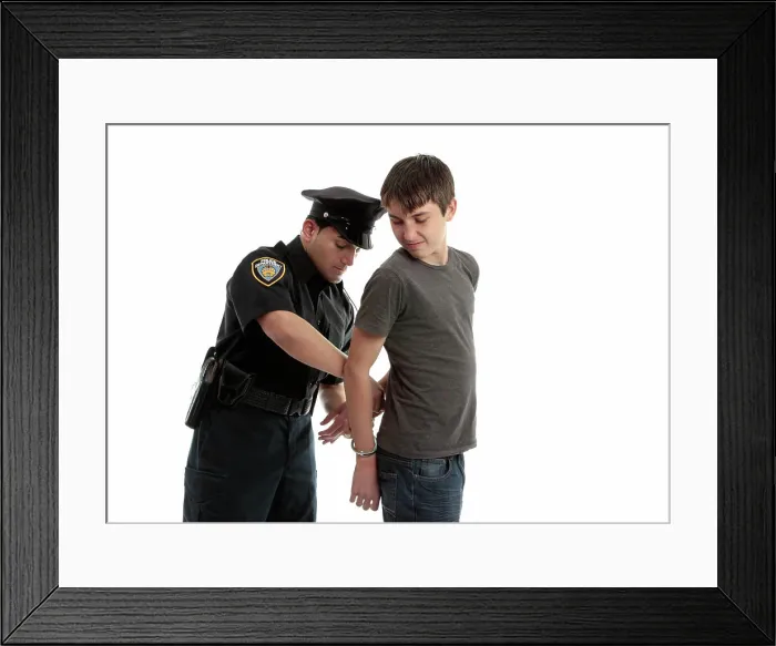 Framed Print : Policeman handcuffing teenager A police officer arrests and handcuffs a young male teen felon Framed Print : Policeman handcuffing teenager A police officer arrests and handcuffs a young male teen felon