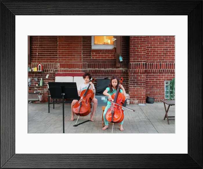 Framed Print : Above-view of two children sitting on patio playing cello Framed Print : Above-view of two children sitting on patio playing cello