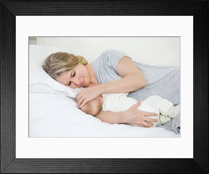 Framed Print : Portrait of a beautiful young smiling mother lying giving breast to her baby Framed Print : Portrait of a beautiful young smiling mother lying giving breast to her baby