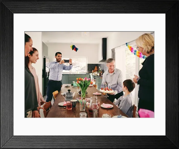 Framed Print : Man photographing boy with family during birthday party through smart phone Framed Print : Man photographing boy with family during birthday party through smart phone
