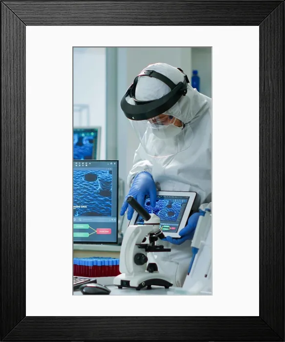 Framed Print : Doctors in coveall discussing about virus development in front of pc and tablet Framed Print : Doctors in coveall discussing about virus development in front of pc and tablet