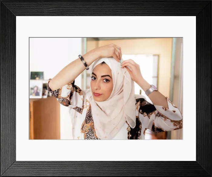 Framed Print : Young muslim woman putting on hijab headscarf Framed Print : Young muslim woman putting on hijab headscarf