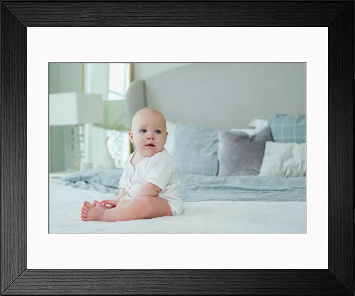 Framed Print : Glückliches Baby. Nettes kleines neugeborenes Mädchen mit lächelndem Gesicht sitzt auf dem Bett im Schlafzimmer Framed Print : Glückliches Baby. Nettes kleines neugeborenes Mädchen mit lächelndem Gesicht sitzt auf dem Bett im Schlafzimmer