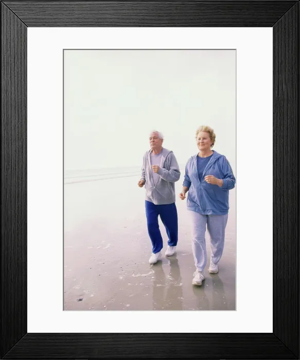 Framed Print : Senior couple jogging at the beach