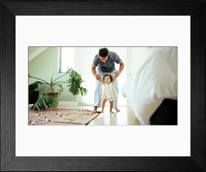 Framed Print : Father, child and learning to walk in home with holding hands