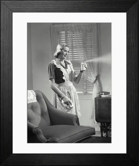 Framed Print : Vintage photograph. Woman in kitchen apron spraying air freshener Framed Print : Vintage photograph. Woman in kitchen apron spraying air freshener