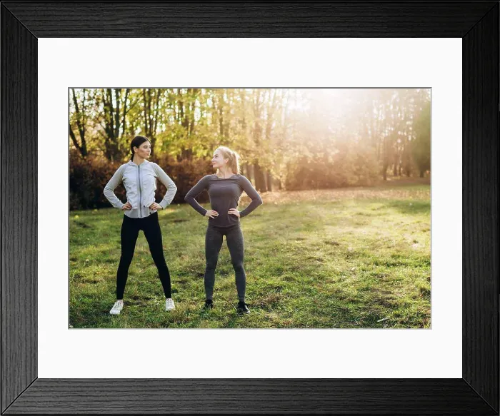 Framed Print : Two girlfriends are doing exercises in nature, looking at each other Framed Print : Two girlfriends are doing exercises in nature, looking at each other