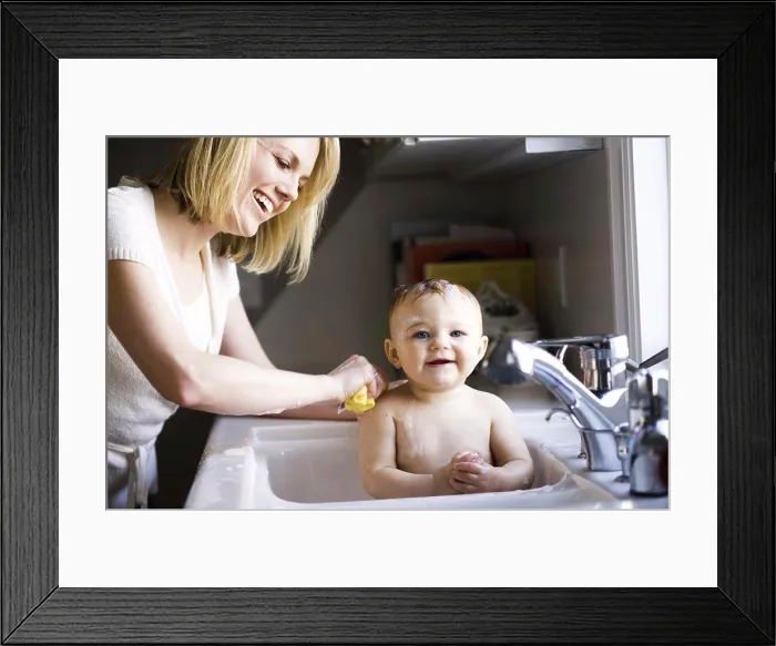 Framed Print : Woman bathing baby in sink Framed Print : Woman bathing baby in sink