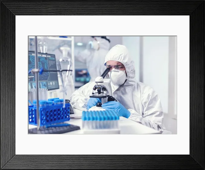 Framed Print : Lab technician in ppe gear examining virus samples under microscope Framed Print : Lab technician in ppe gear examining virus samples under microscope