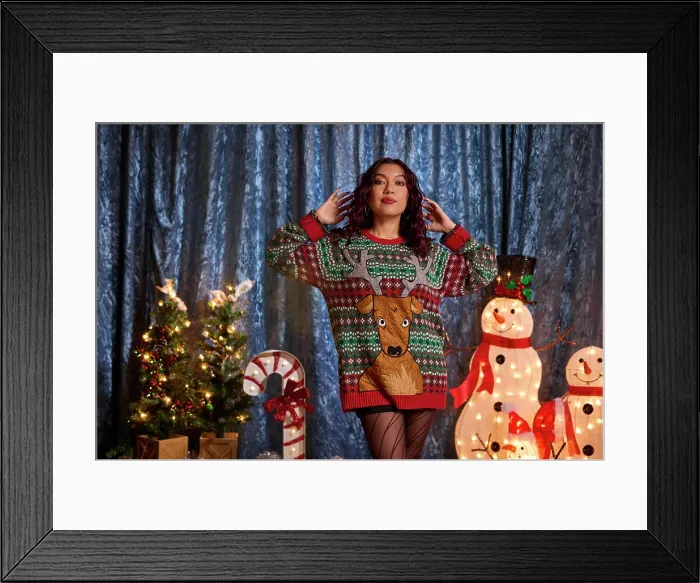 Framed Print : Woman wearing festive reindeer ugly Christmas sweater poses with holiday decorations and illuminated snowmen