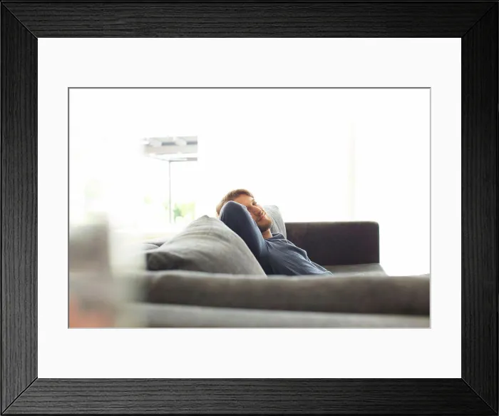 Framed Print : Smiling man relaxing on sofa
