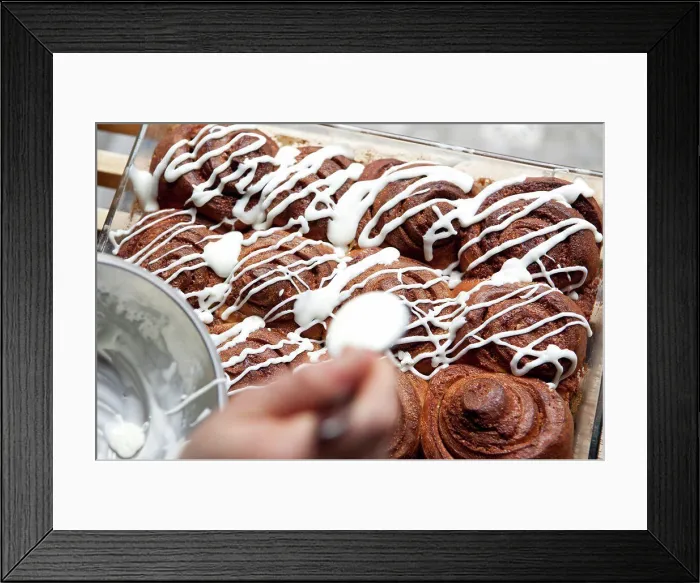 Framed Print : A coffee shop employee putting icing on a cinnamon rolls Framed Print : A coffee shop employee putting icing on a cinnamon rolls