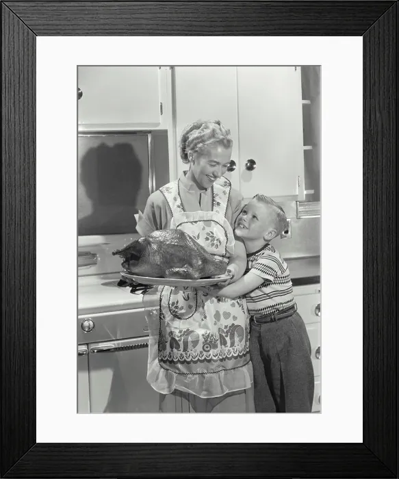 Framed Print : Mid adult woman holding a roast turkey with her son hugging her Framed Print : Mid adult woman holding a roast turkey with her son hugging her