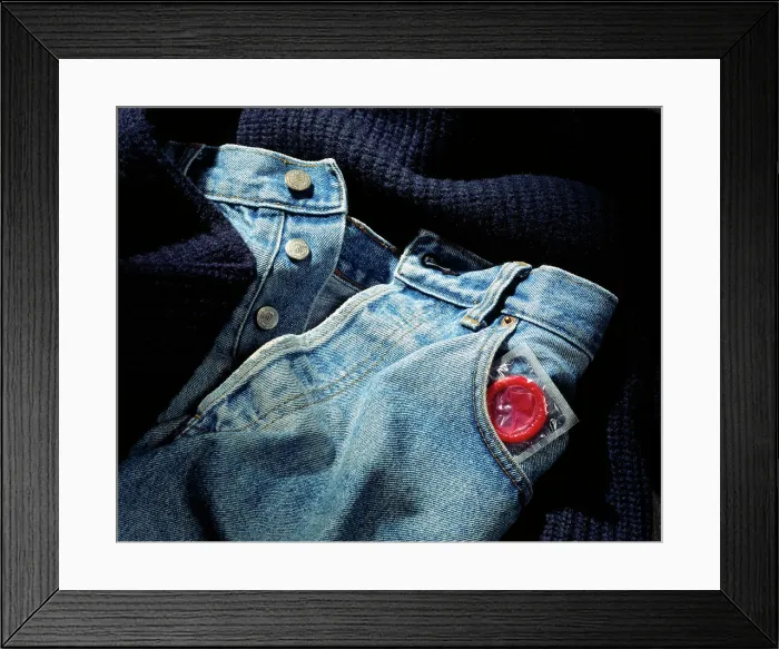 Framed Print : Sealed condom poking out of a jeans pant pocket Framed Print : Sealed condom poking out of a jeans pant pocket