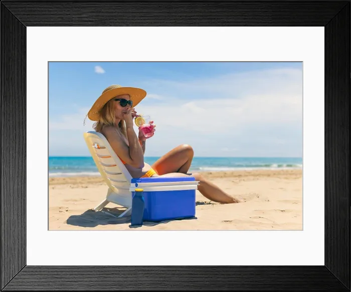 Framed Print : Happy young european girl drinks a cocktail and rests in a sun lounger on the beach Framed Print : Happy young european girl drinks a cocktail and rests in a sun lounger on the beach
