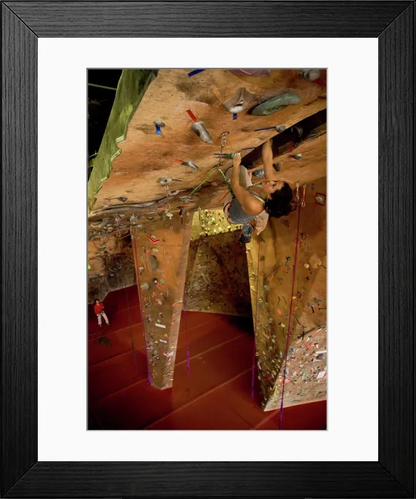 Framed Print : A female rock climber lead climbs in an indoor rock climbing gym Framed Print : A female rock climber lead climbs in an indoor rock climbing gym