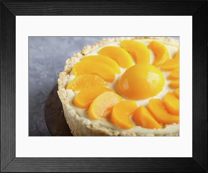 Framed Print : Round peach cheesecake on a gray concrete background. side view, close up