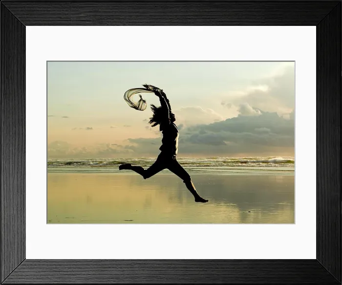 Framed Print : A woman with a scarf leaps on the beach in Newport, Oregon