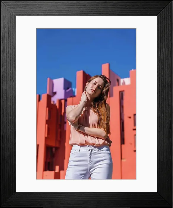 Framed Print : Lifestyle of a young caucasian woman in a salmon colored shirt and white pants in some colored houses