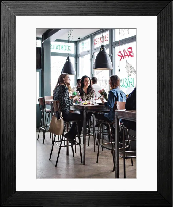 Framed Print : Full length of smiling female friends sitting with birthday presents at dining table in restaurant Framed Print : Full length of smiling female friends sitting with birthday presents at dining table in restaurant