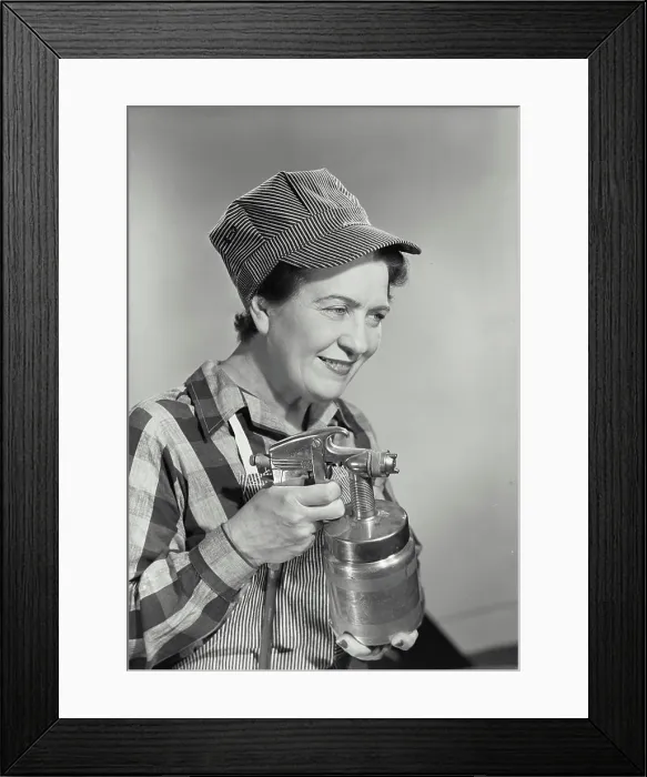 Framed Print : Vintage photograph. Middle aged woman dressed in work uniform holding paint sprayer with fingers on trigger