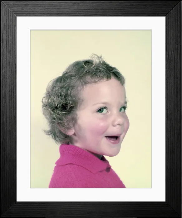 Framed Print : Adorable toddler with curly hair in a pink sweater smiling playfully Framed Print : Adorable toddler with curly hair in a pink sweater smiling playfully