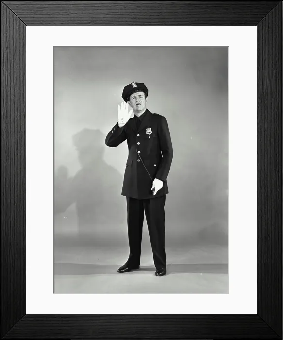 Framed Print : Vintage photograph. Full length portrait of policeman with whistle with hand raised looking concerned