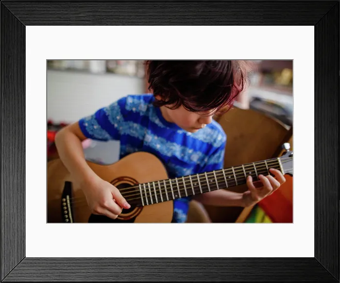 Framed Print : Tween boy tenderly plays an acoustic guitar on front porch of home Framed Print : Tween boy tenderly plays an acoustic guitar on front porch of home