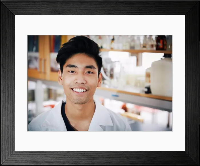 Framed Print : Portrait of confident young male university student standing at chemistry laboratory