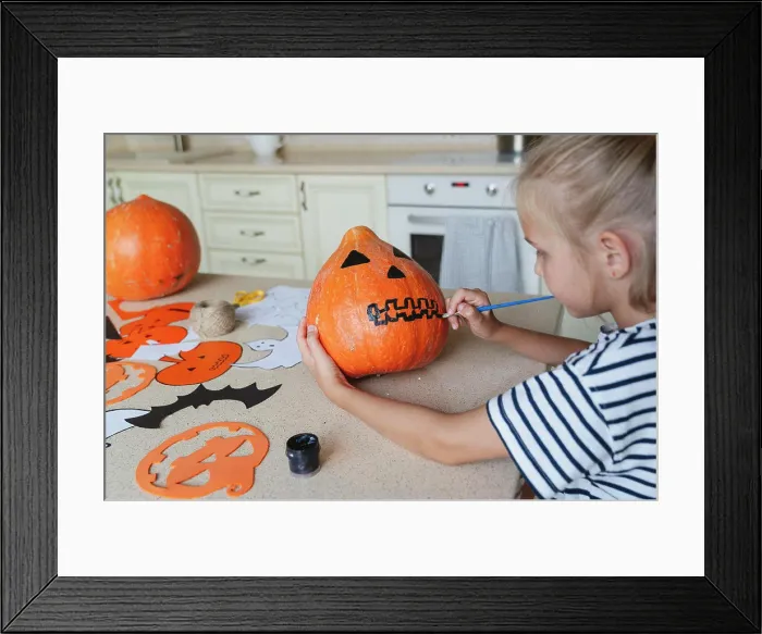 Framed Print : Girl decorating and painting pumpkin for Halloween