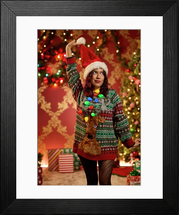 Framed Print : Woman wearing festive ugly Christmas sweater with reindeer and lights holding Santa hat Framed Print : Woman wearing festive ugly Christmas sweater with reindeer and lights holding Santa hat
