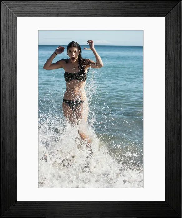 Framed Print : Woman in a bikini enjoys the ocean waves splashing around her on a sunny day Framed Print : Woman in a bikini enjoys the ocean waves splashing around her on a sunny day
