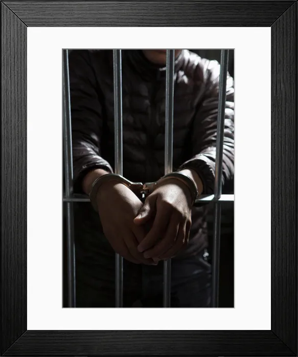 Framed Print : A prisoner behind bars with hands cuffed Framed Print : A prisoner behind bars with hands cuffed