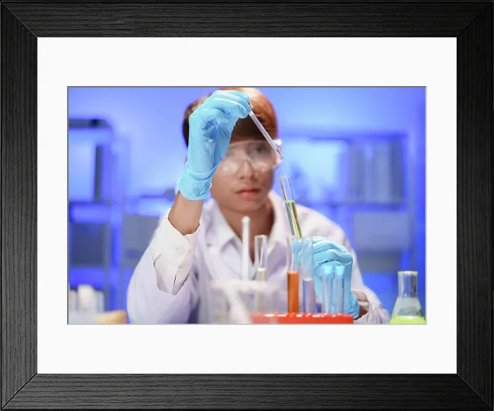 Framed Print : Wissenschaftler, die im Labor arbeiten und mit einer Pipette eine flüssige Probe in ein Reagenzglas tropfen