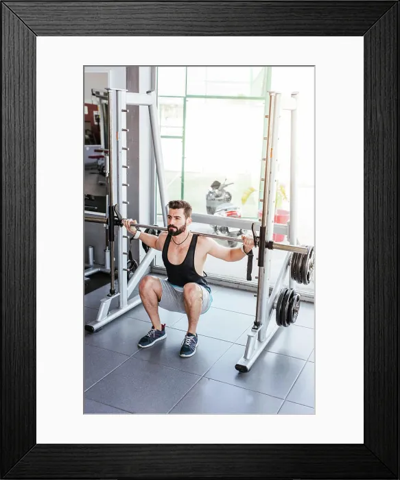 Framed Print : Powerful determined sportsman doing exercise with barbell at squat rack during weightlifting training with personal Framed Print : Powerful determined sportsman doing exercise with barbell at squat rack during weightlifting training with personal