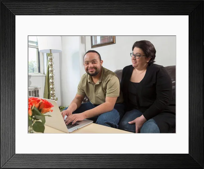 Framed Print : African American man with Down Syndrome using a laptop with his mother at home