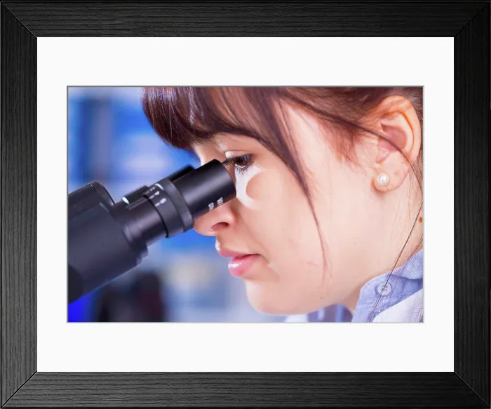 Framed Print : MODEL RELEASED. Woman using microscope, close up