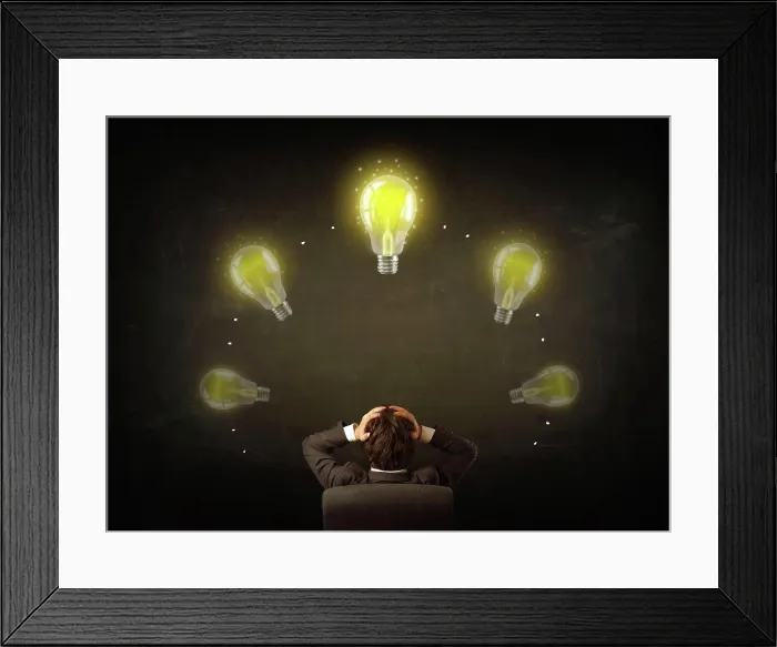 Framed Print : Geschäftsmann sitzt mit Lichtböcken über seinem Kopf Young businessman sitting in office chair in front of a balckboard