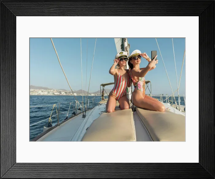 Framed Print : Beautiful young females in sunglasses and captain hats taking selfie on mobile phone Framed Print : Beautiful young females in sunglasses and captain hats taking selfie on mobile phone